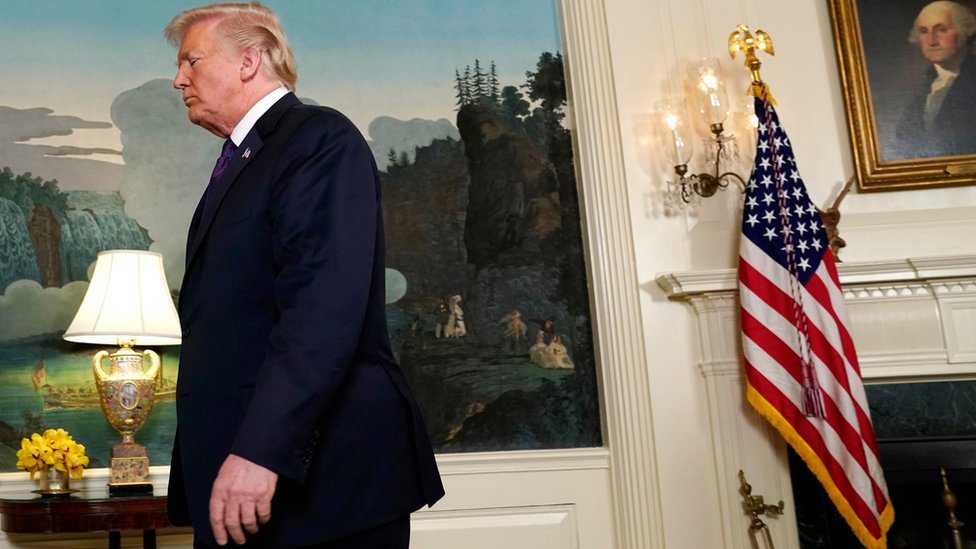 Donald Tramp izlazi sa konferencije za štampu, američka zastava u pozadini