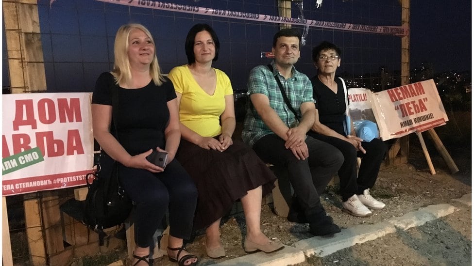 Zašto su stanarima Stepe obećane škole i vrtići, a dobijaju crkvu 3 Četvero stanara sede noću ispred žičane ograde sa transparentima