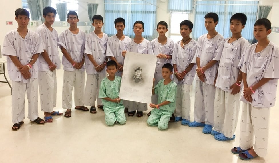 Članovi kluba "Divlji veprovi" i njihov trener spaseni iz poplavljene pećine fotografisani u bolnici u Čang Rai sa portretom ronioca Samana Gunana, koji je poginuo u akciji spasavanja dečaka iz pećine.