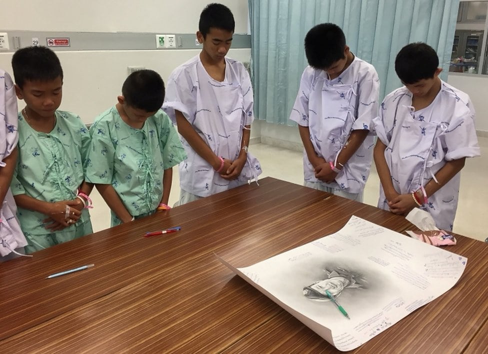 Članovi tima okupljeni oko crteža ronioca Samana Gunana na kom su napisali poruke saučešća