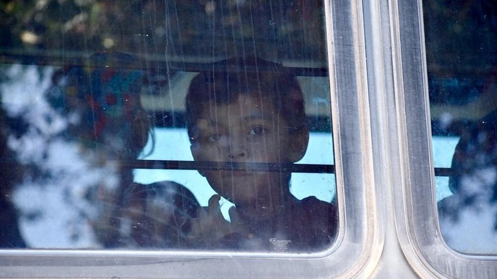 Dete migrant gleda kroz prozor autobusa