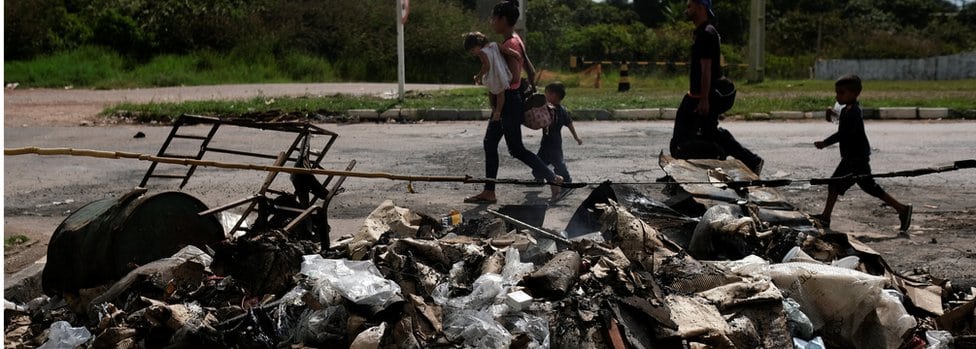 Državljani Venecuele prolaze pored spaljenih šatora i stvari u Roraimi, 19. avgusta 2018