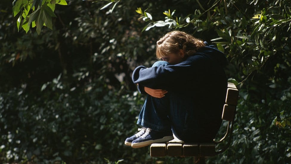 Devojčica usamljeno sedi na klupi