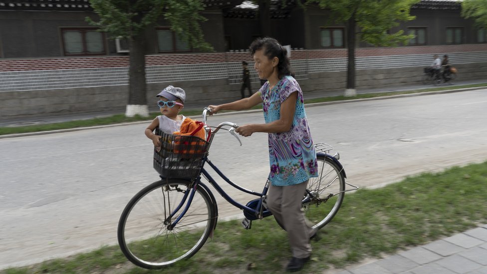 U fotografijama : Odrastanje u Severnoj Koreji 7 A mother watches her child, who sits in the basket of a bicycle