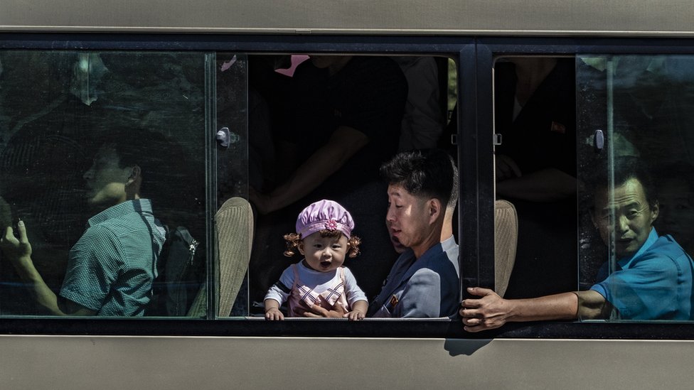 U fotografijama : Odrastanje u Severnoj Koreji 14 Baby looking out of a Pyongyang bus while her father holds her secure