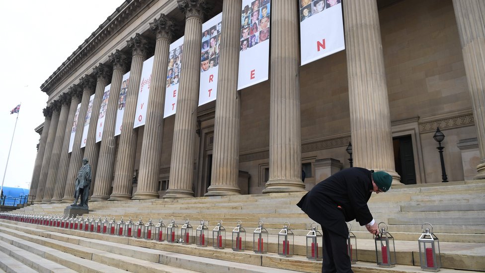 A man lights 96 lanterns arranged on the steps of St George's Hall in Liverpool