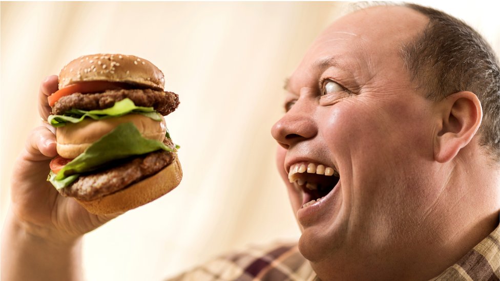 čovek jede hamburger