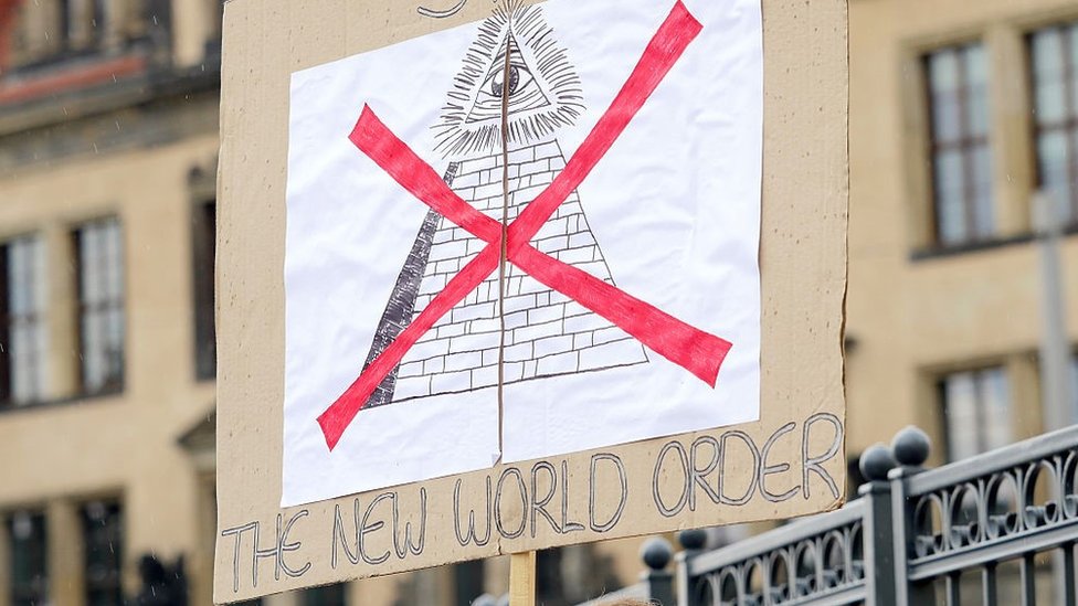 Demonstrant nosi parolu na kojoj piše „Stop novom svetskom poretku"