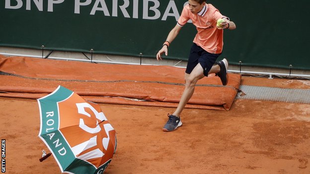 An umbrella blows onto the court