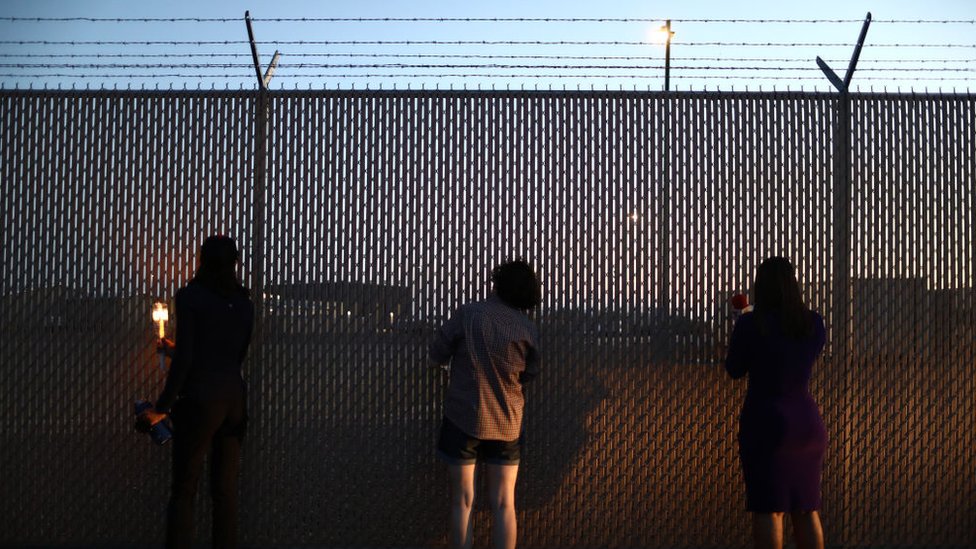 Ljudi gledaju kroz ogradu koja obezbeđuje stanicu granične policije u Klintonu, Teksasu