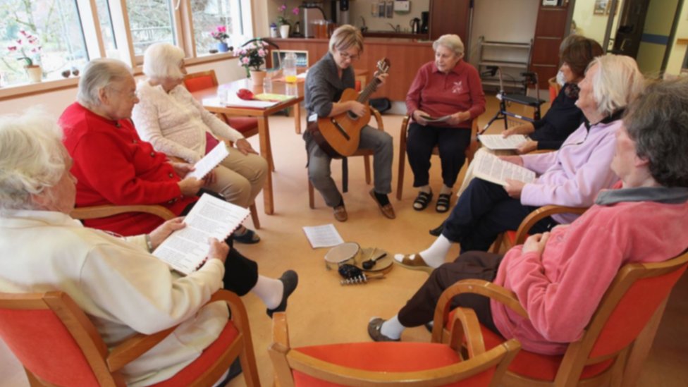People in a residential care home for Alzheimer's disease and dementia patients sing together with a social therapist