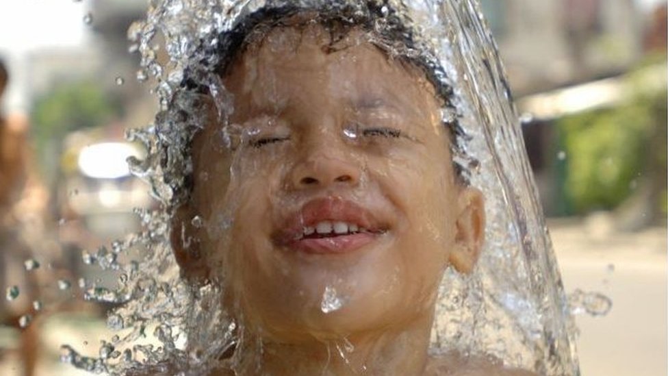 A young FIlipino boy enjoys a bath on a Manila street