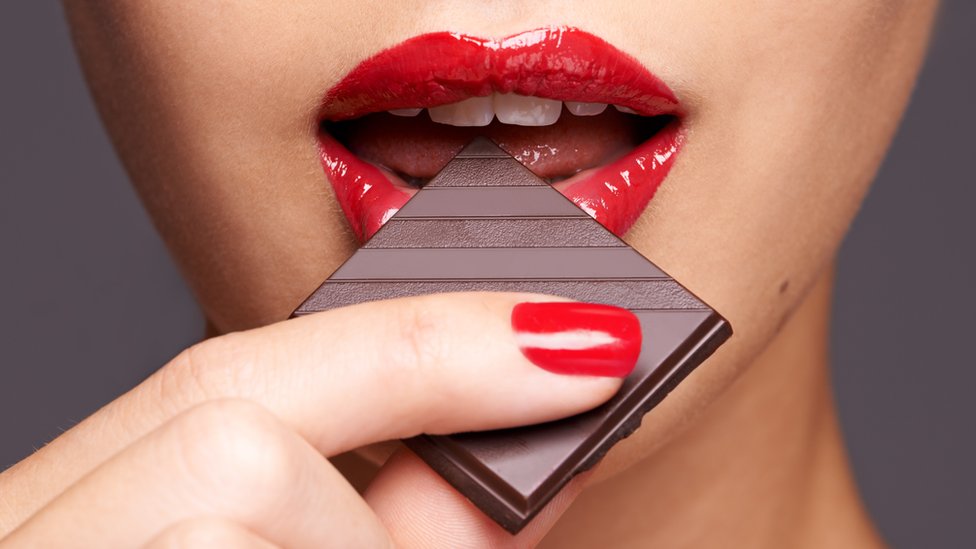 Ženske usne koje grckaju parče čokolade