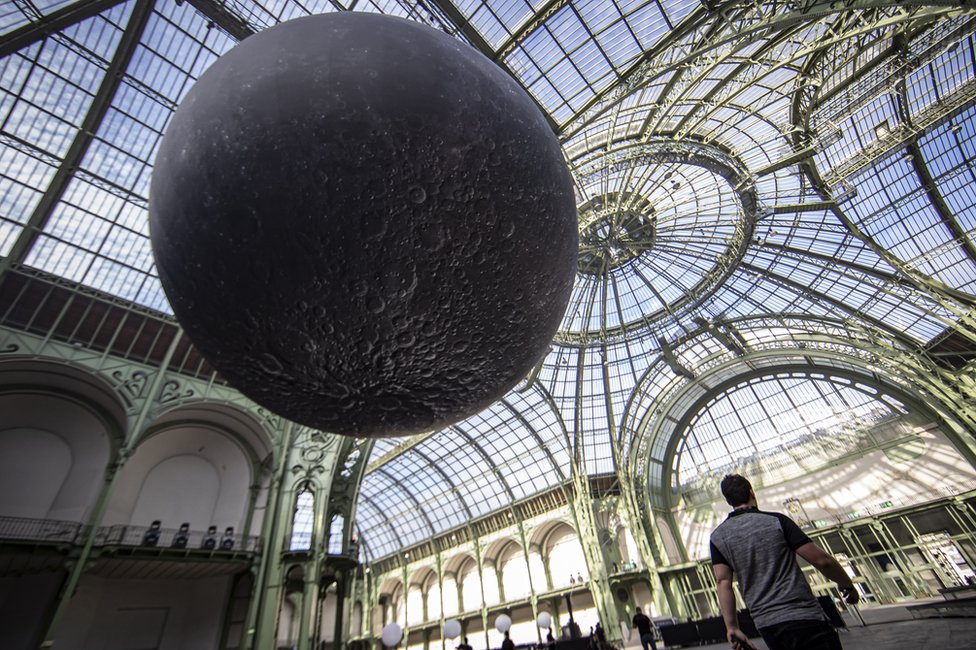 A replica of the moon hangs from the glass ceiling of the Grand Palais ahead of the "Mooon Party" celebrating the 50th anniversary of the moon landing, in Paris, France