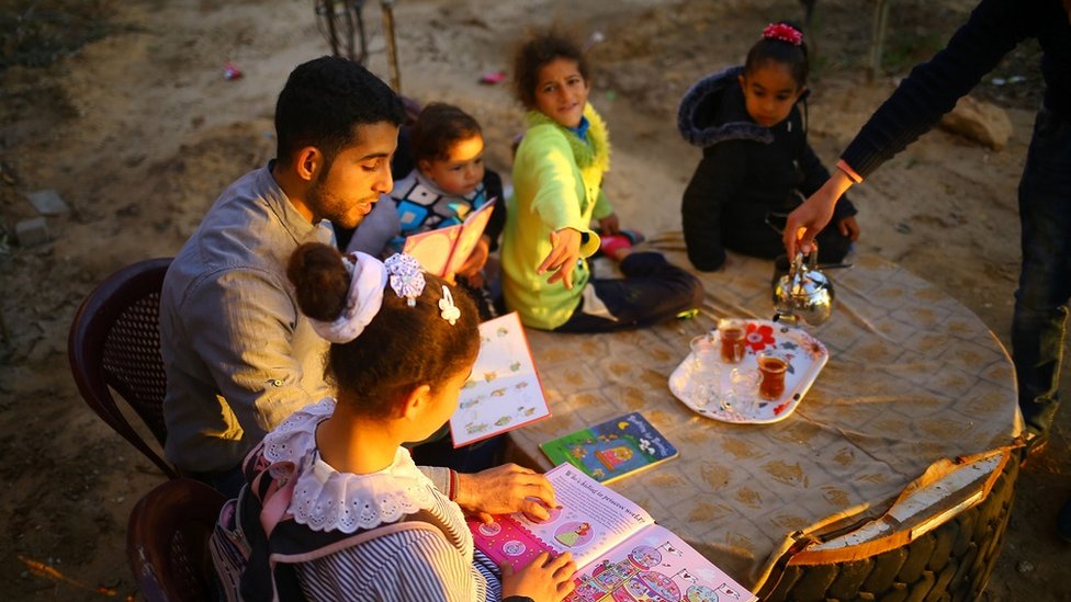 A man reads to a group of children in a Palestinian garden