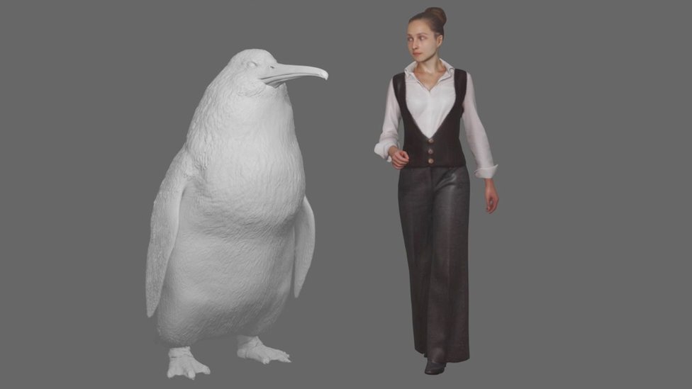 A model of the penguin standing next to a woman for scale