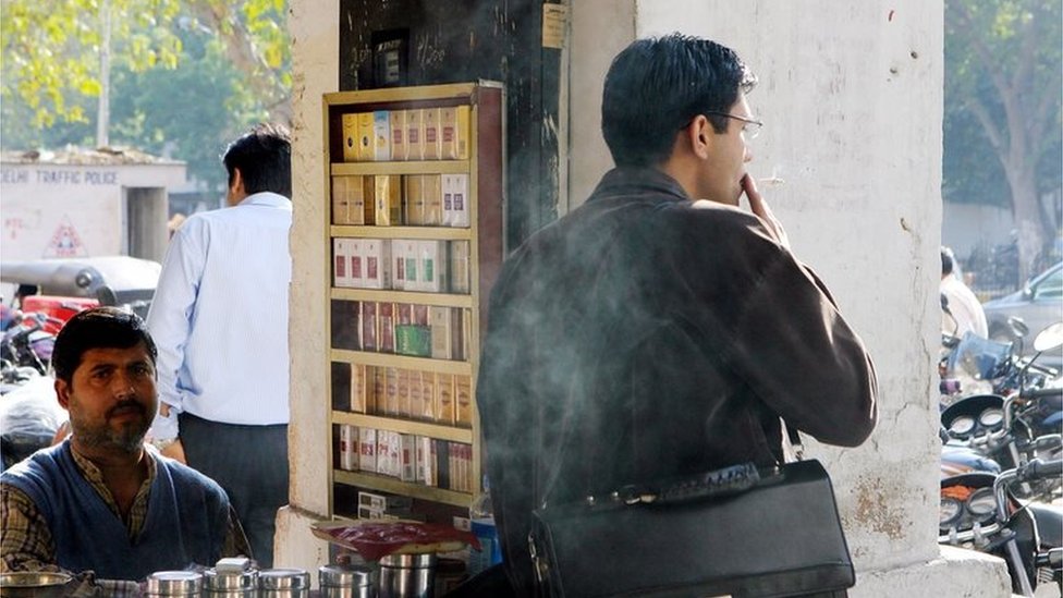 A cigarette vendor looks on as one of his customers smokes in Delhi (file photo)