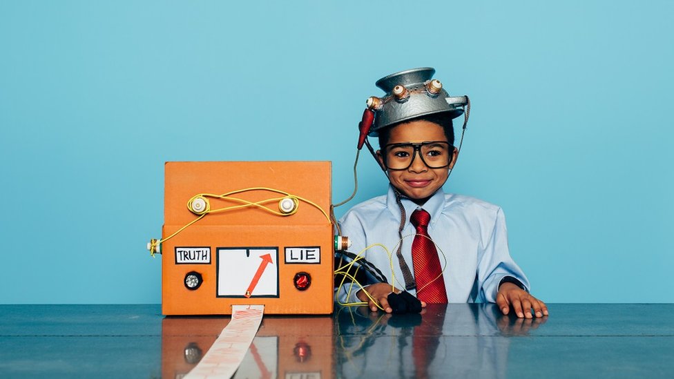 A child dressed up as a businessman, with a homemade "lie detector" fashioned from a cardboard box