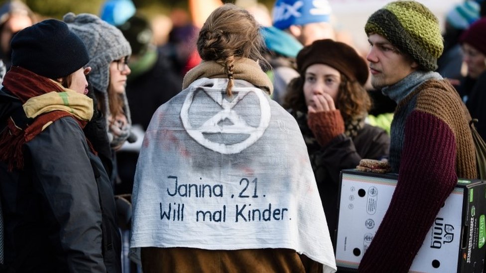 Pobuna protiv izumiranja: Hapšenja u Sidneju i Amsterdamu 3 Aktivistkinja u Berlinu nosi plašt na kome piše „Džanina, 21, volela bi da ima decu"