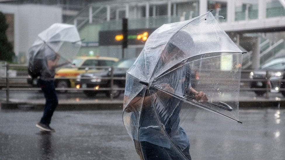 Tajfun Hagibis: Sedam miliona Japanaca mora da se evakuiše 4 People shelter under umbrellas from the wind and rain as they cross a road near Shinjuku train station on October 12, 2019 in Tokyo, Japan