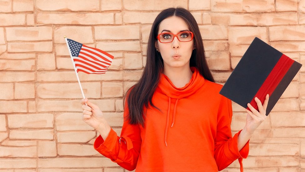 Želite li da poboljšate znanje engleskog? Evo kako da pišete dobro na „najagresivnije nepravilnom jeziku na svetu“ 2 A young woman whistling, holding an American flag