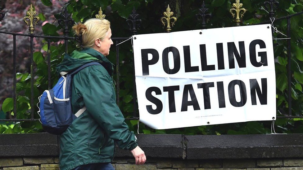 Woman walking past polling station sign