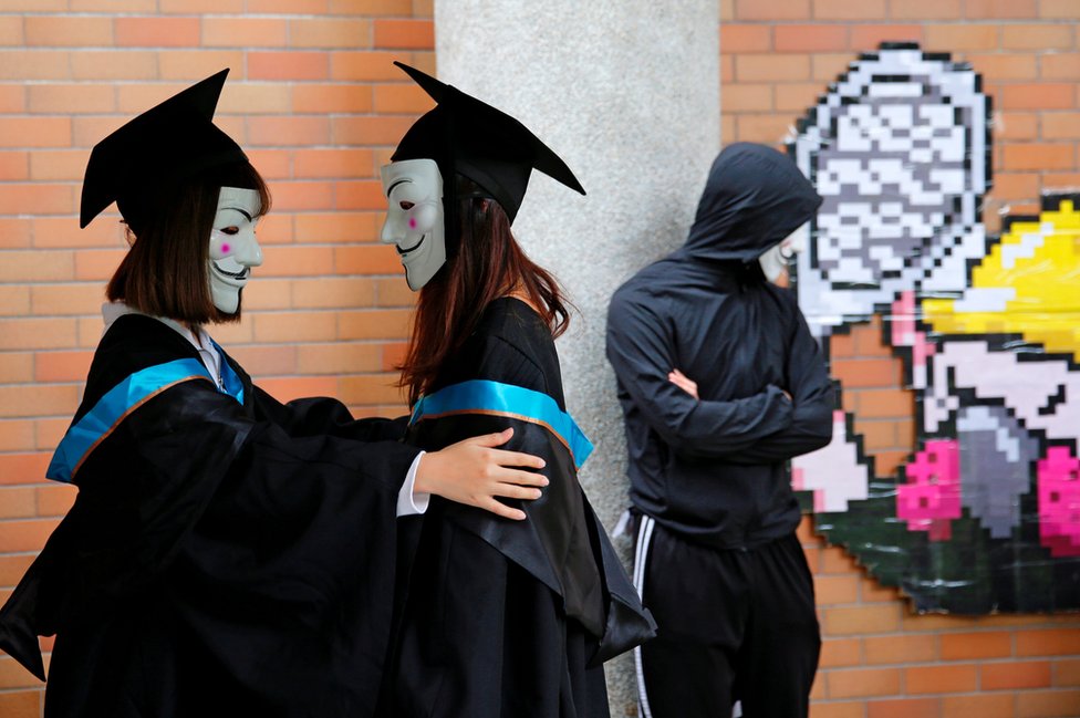 University students wearing Guy Fawkes masks pose for a photoshoot