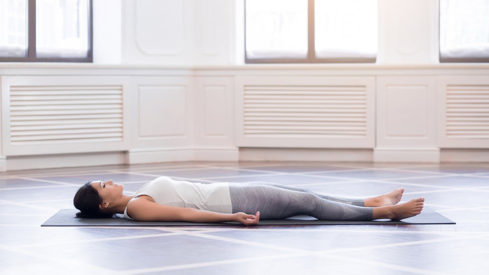 A woman relaxing on a floormat in an empty room