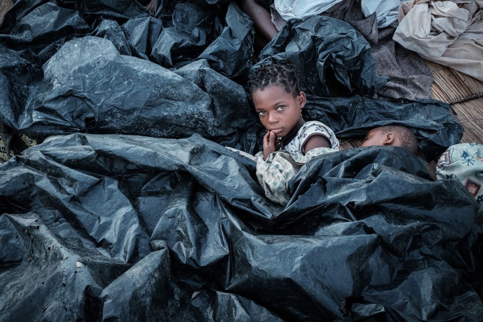 Enia Joaquin Luis, 11, wakes up beside her sister Luisa, 6, under plastic sheets to protect themselves from rain at a shelter in Buzi, Mozambique, following Cyclone Idai in March.