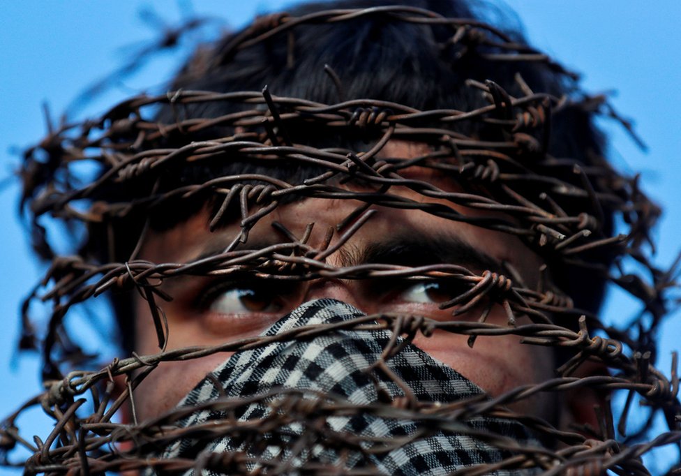A masked Kashmiri man with his head covered with barbed wire attends a protest in Srinagar in October following the scrapping of the special constitutional status for Kashmir by the Indian government.