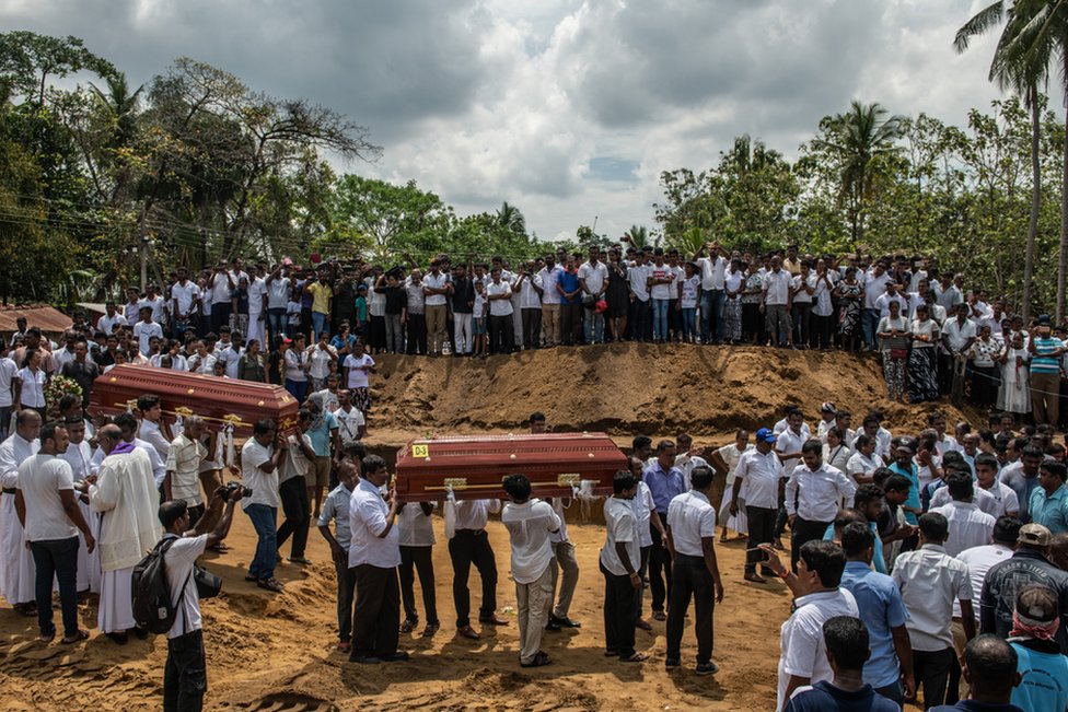 Coffins are carried to a grave during a mass funeral at St Sebastian's Church on 23 April in Negombo, Sri Lanka.