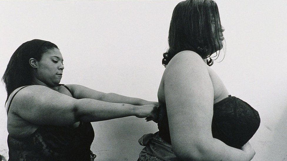 A plus-size woman helps another to dress