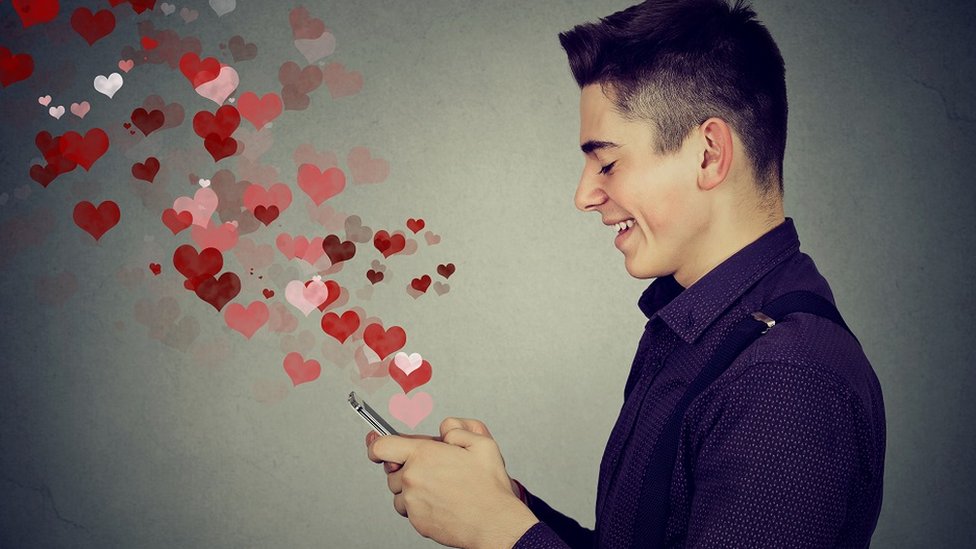 A young man using a smartphone to send love messages