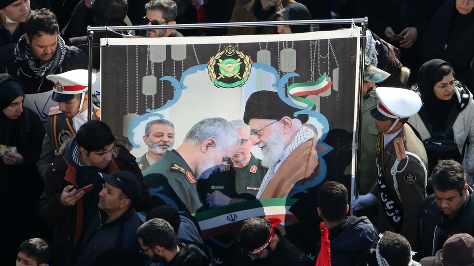 Mourners hold up a picture of Iran's supreme leader and Qasem Soleimani