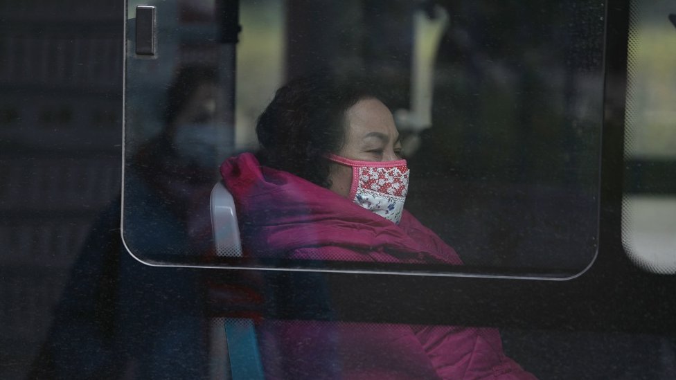 A woman wears a mask as she rides a bus near the closed Huanan Seafood Wholesale Market in China