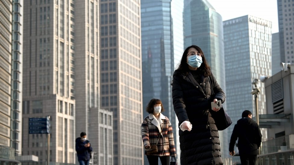 People wearing protective face masks walk on an overpass in Shanghai on February 24, 2020