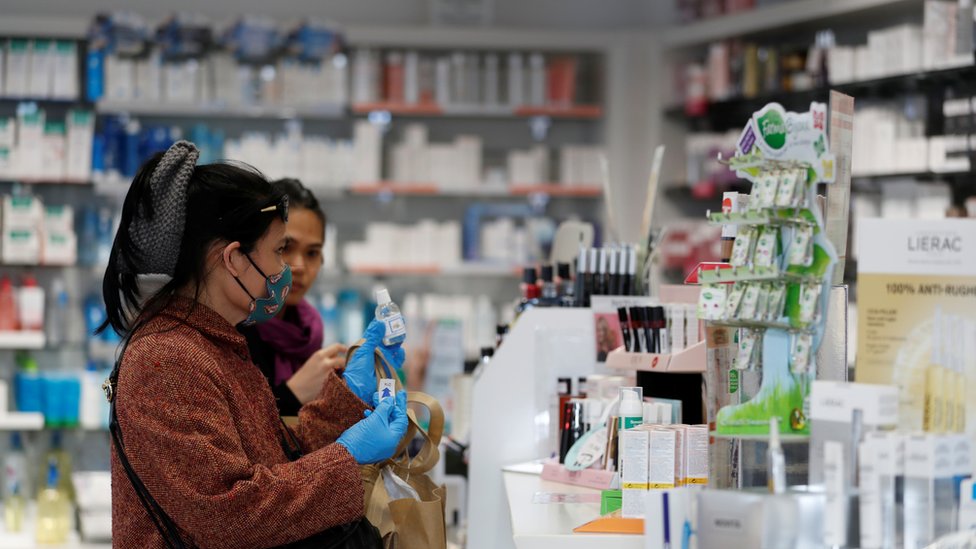Two women try to buy sanitiser in a shop in Milan