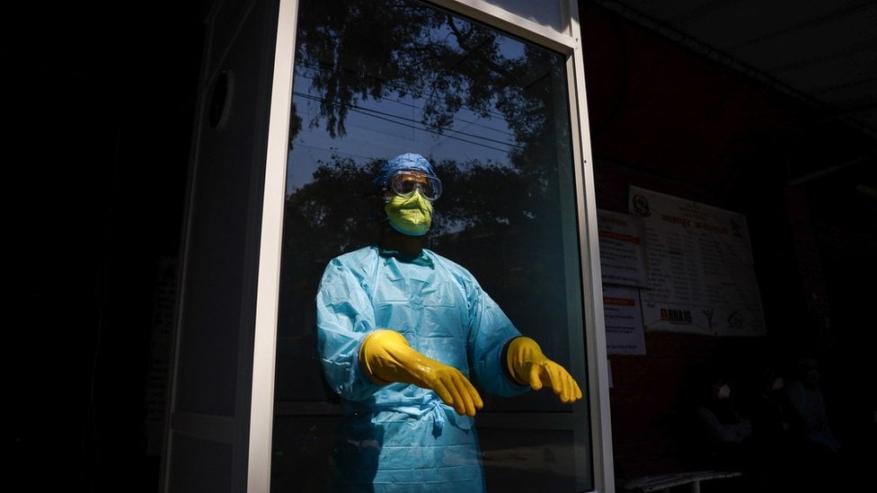 A medical person stands inside a corona virus check-up booth wearing proper protective gear at Bhaktapur Hospital, Nepal, during the fifteenth day of a nationwide lockdown.