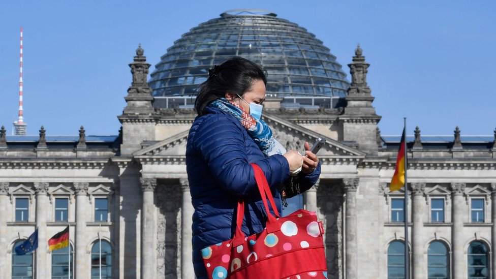 Korona virus: Zašto je teško praviti poređenja među zemljama sa epidemijom Kovida-19 1 Woman walks past Reichstag wearing a mask