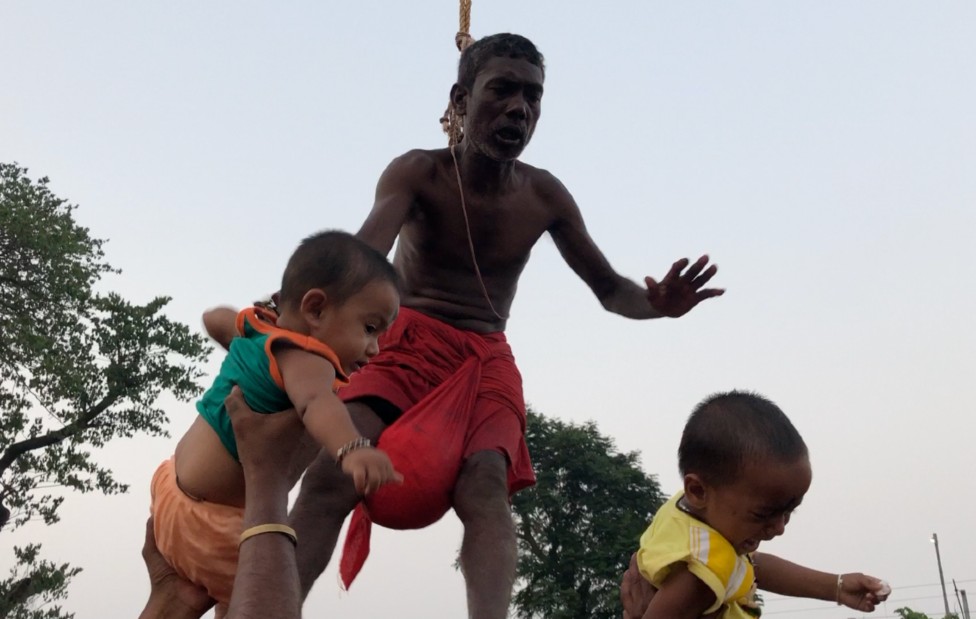 Babies are passed to a devotee suspended by his back