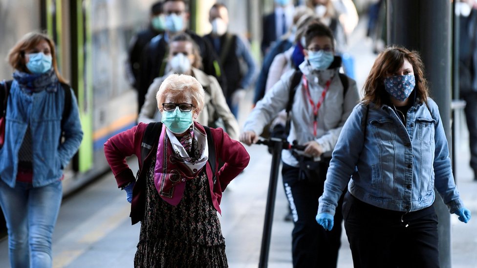 Passengers in masks arrive at a railway station in Milan (3 May)
