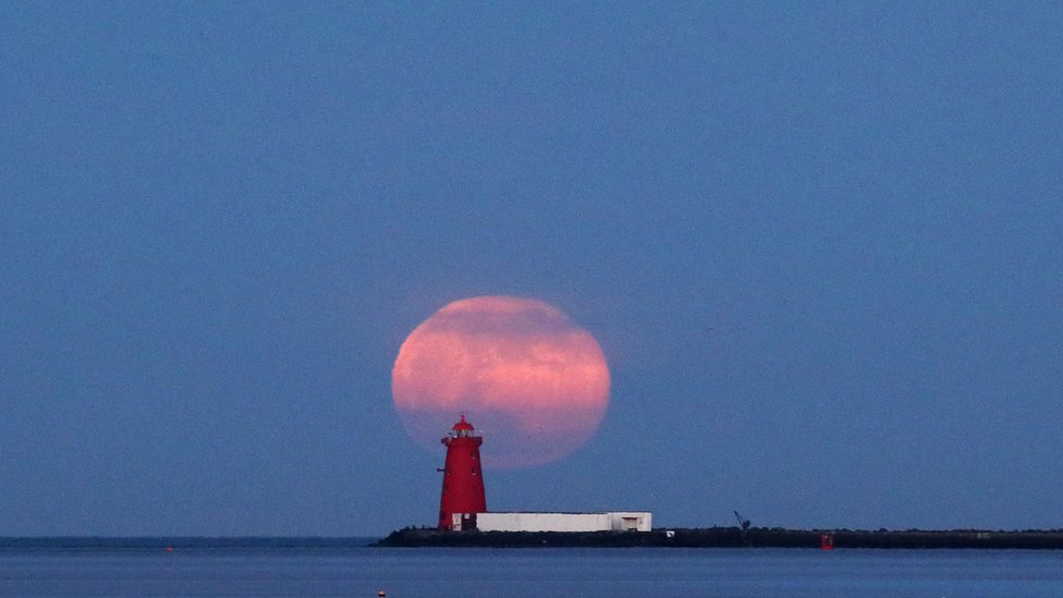 The final supermoon of the year rises over Poolbeg Lighthouse in Dublin Bay, Ireland