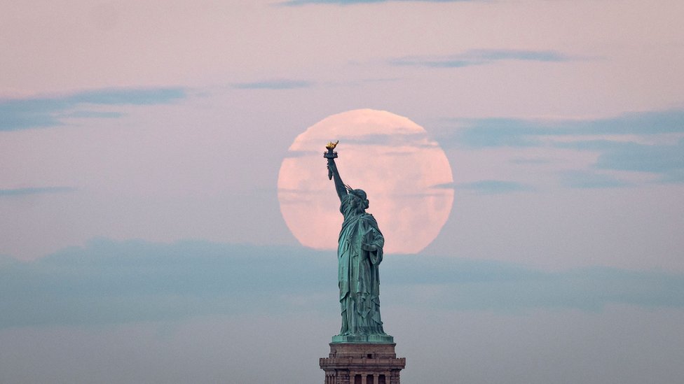 May"s full Moon, known as the Full Flower Moon and is the last supermoon of the year, sets behind the Statue of Liberty in New York City