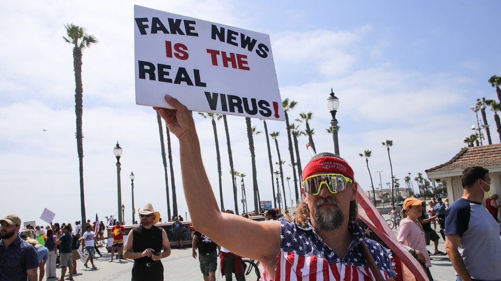 Transparent demonstranta izražava sumnju u postojanje korona virusa tokom protesta u Kaliforniji s početka maja