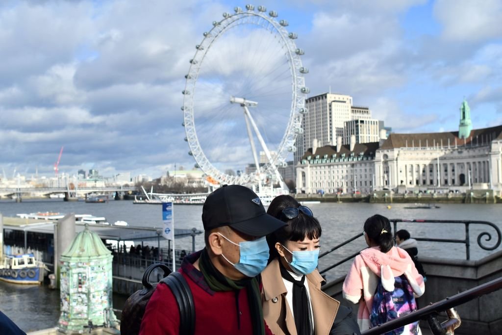 A couple wear face masks as they walk along the Thames embankment in central London