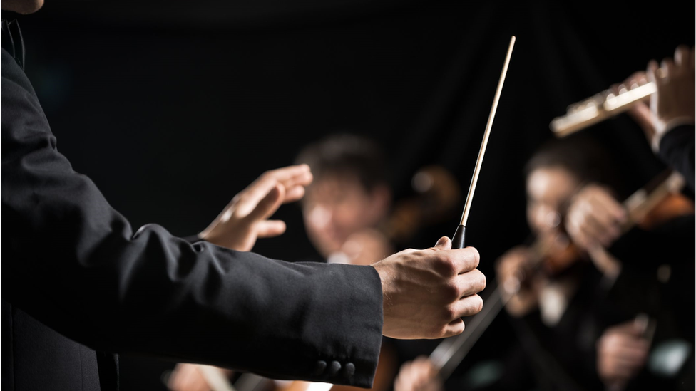 A maestro conducting an orchestra