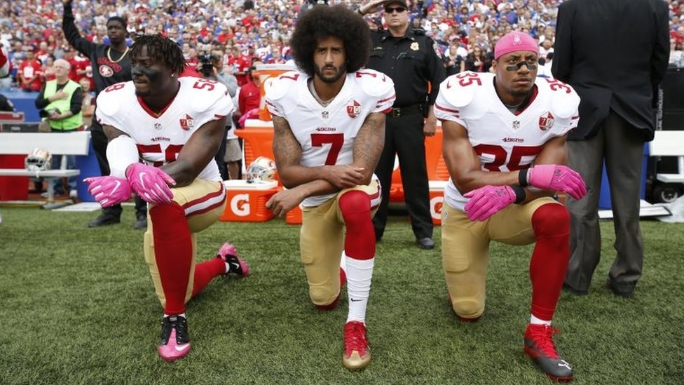 Colin Kaepernick (centre) and two players from the San Francisco 49ers kneel during the national anthem in New York. Photo: October 2016
