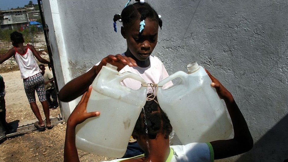 Devojčica nosi kanistere sa vodom na Haitiju