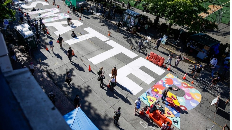Smrt Džordža Flojda: Demonstranti u Sijetlu formirali zonu bez policije, Tramp preti intervencijom 3 The words 'Black Lives Matter' are painted in the middle of East Pine Street in the Chaz