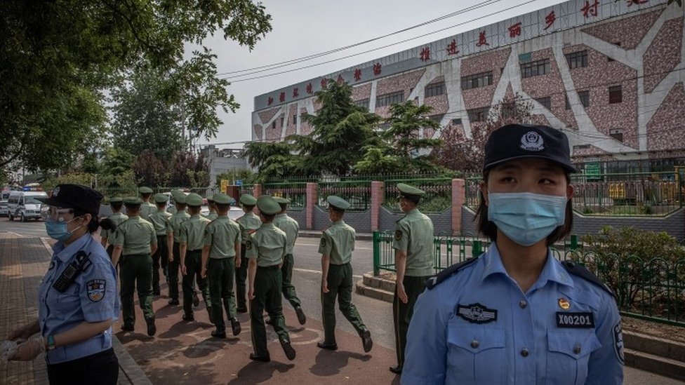 Chinese police officers wearing face masks stand guard next to the closed Xinfadi market building in Fengtai district, Beijing, China, 13 June 2020.